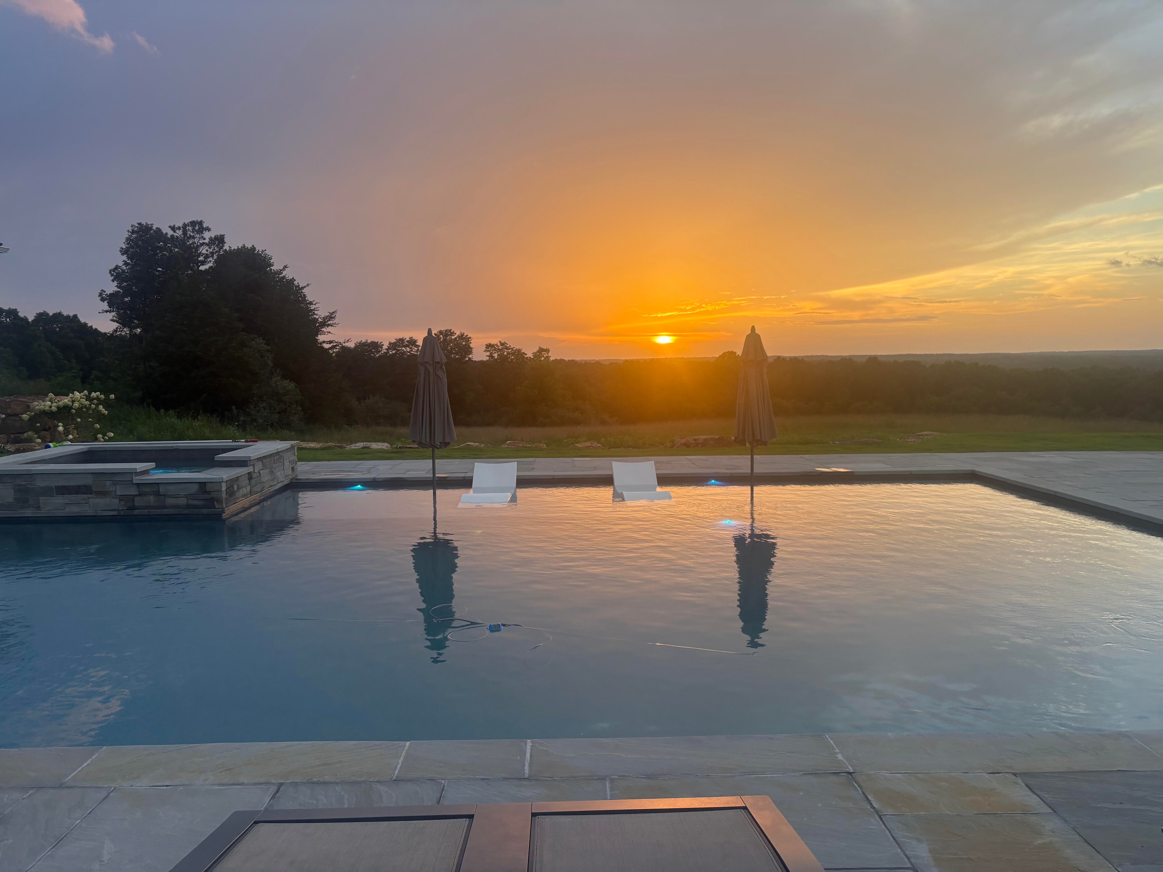 Infinity pool at golden hour sunset with lounge chairs